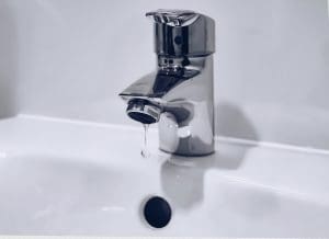 chrome tap over a white porcelain basin that is dripping