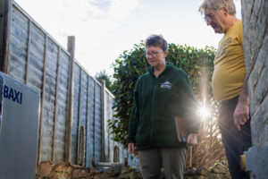 Two people standing outside looking at a heat pump